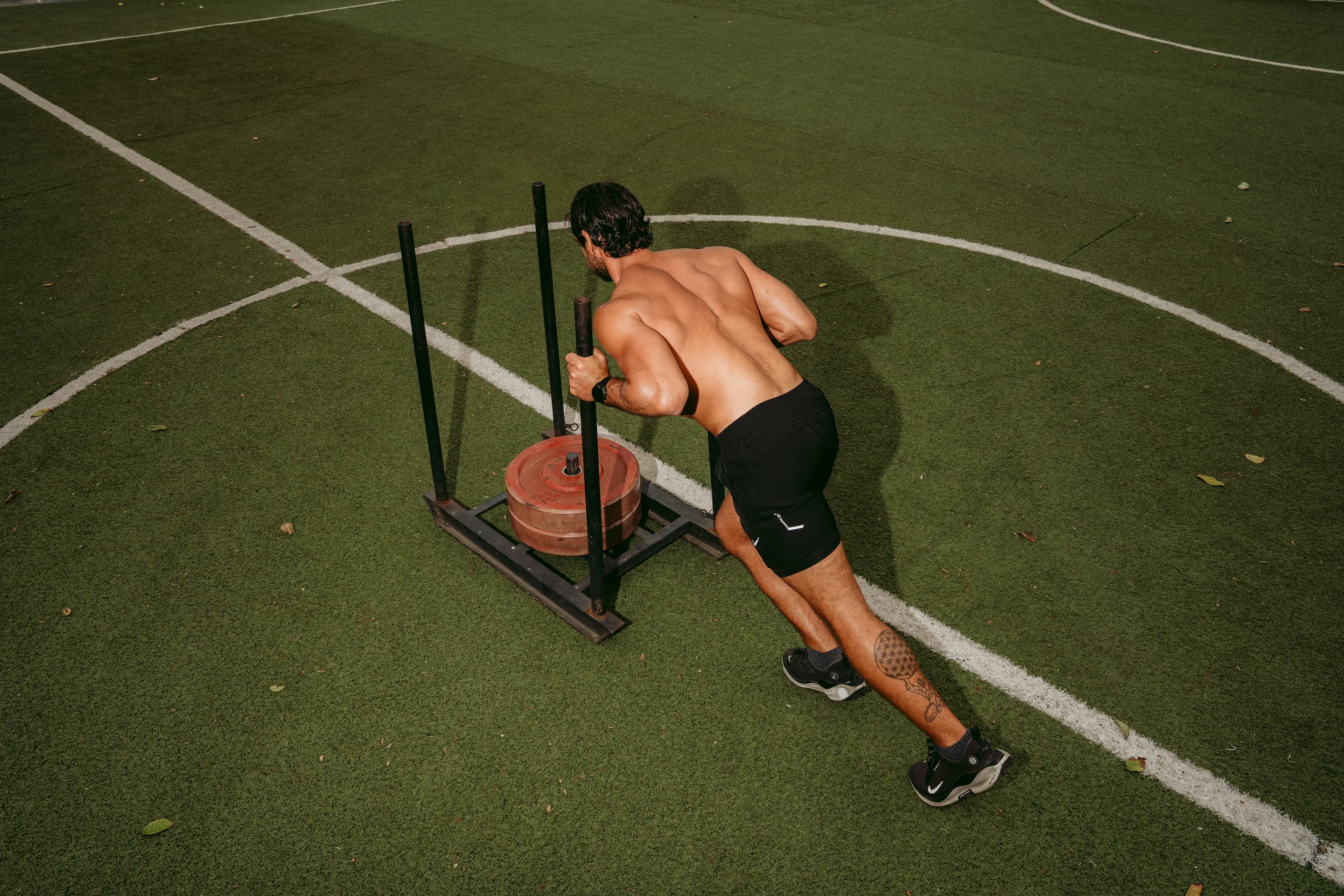 An athlete pushing a weighted sled across the training pitch
