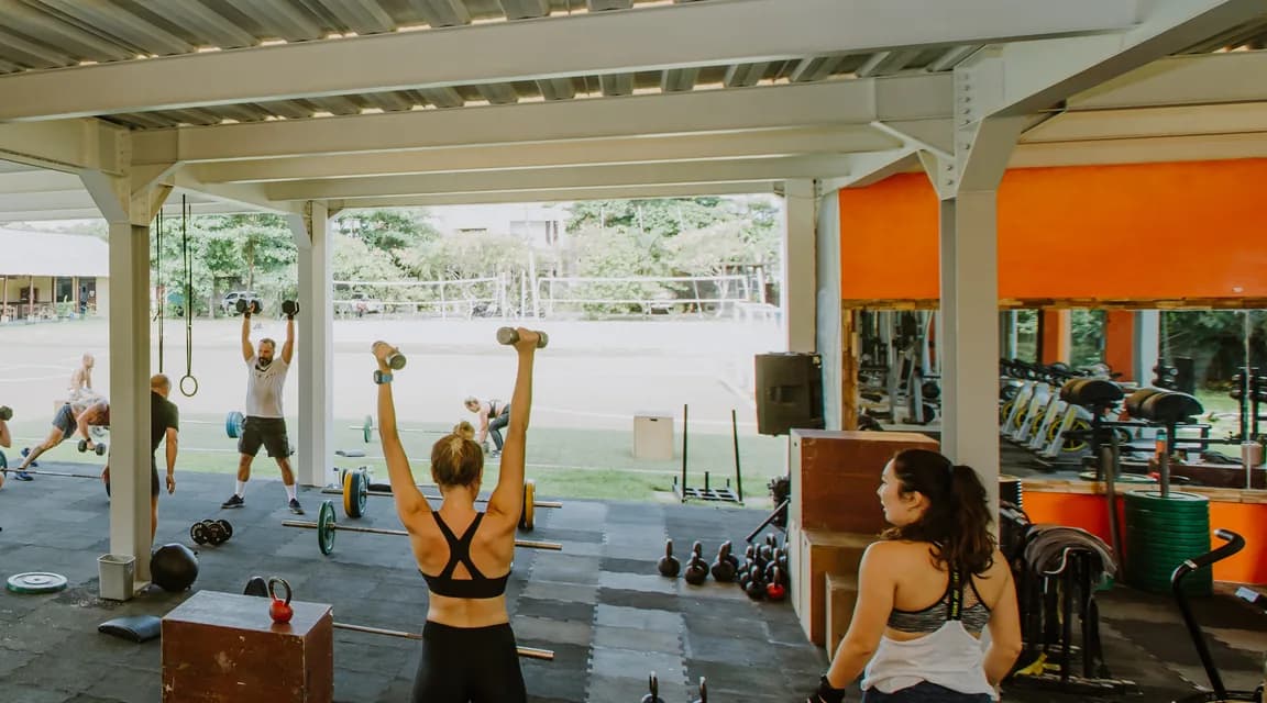 Guests training with dumbbells and barbells in the open-air gym