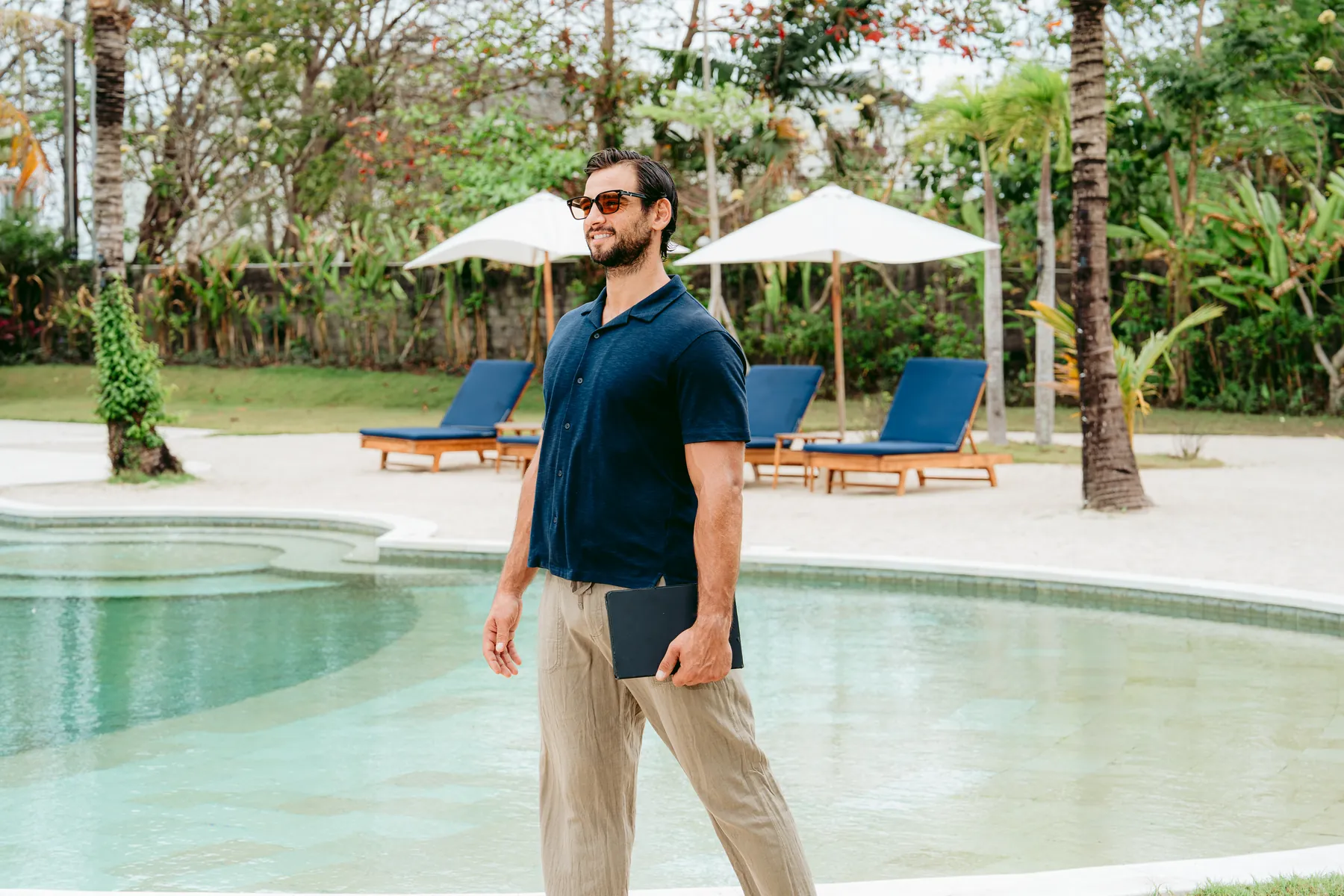 A guest carrying a tablet past the pool