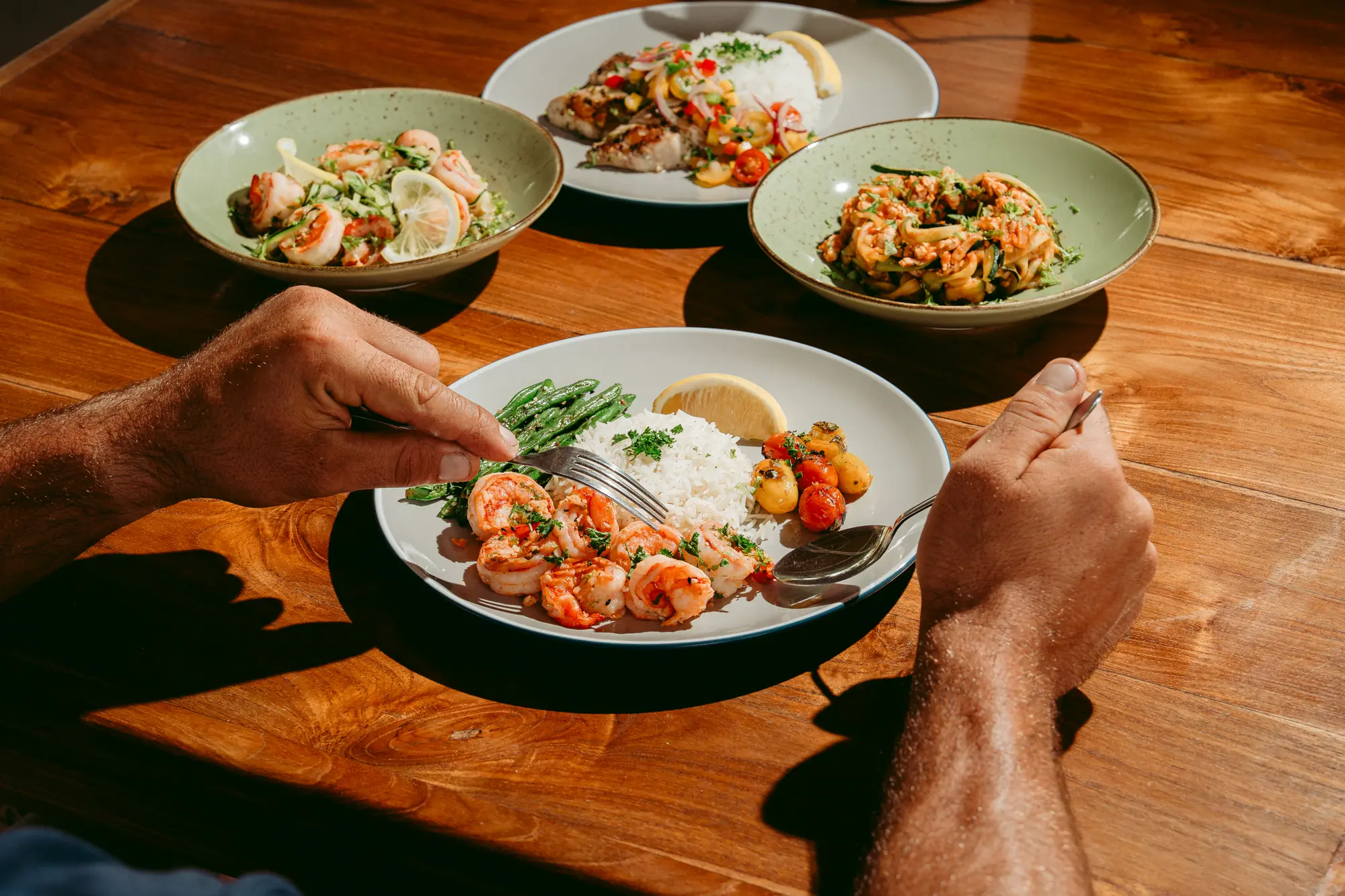 Guests sharing plates of seafood, rice and salads at a wooden table