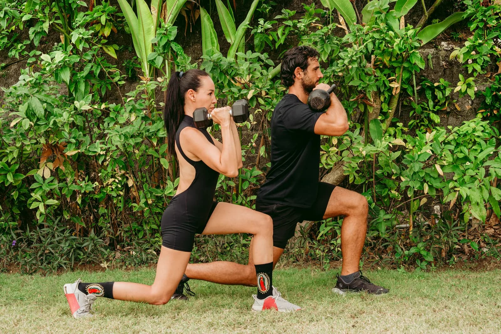 Two guests doing dumbbell lunges on the lawn