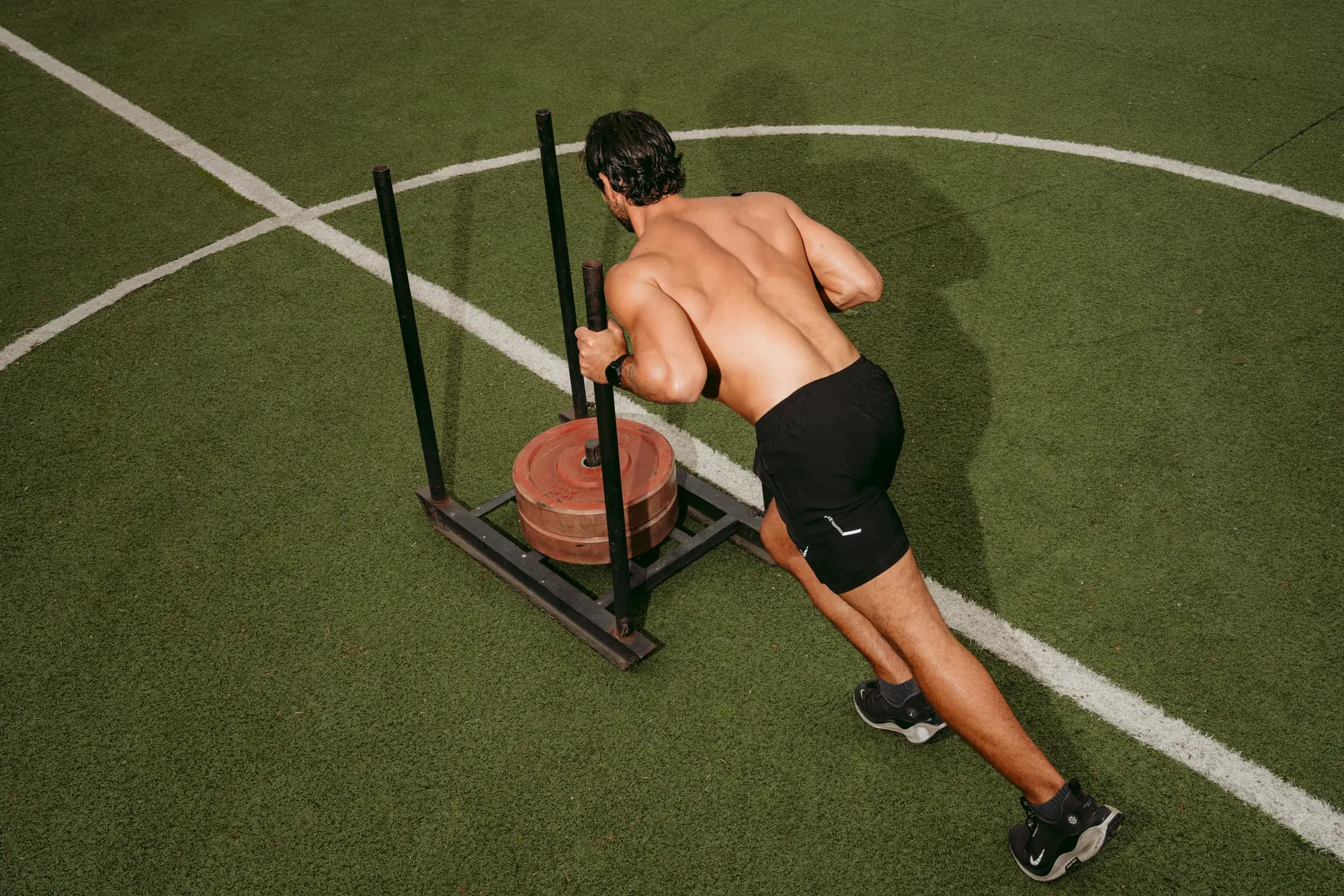 A guest pushing a weighted sled across the training turf