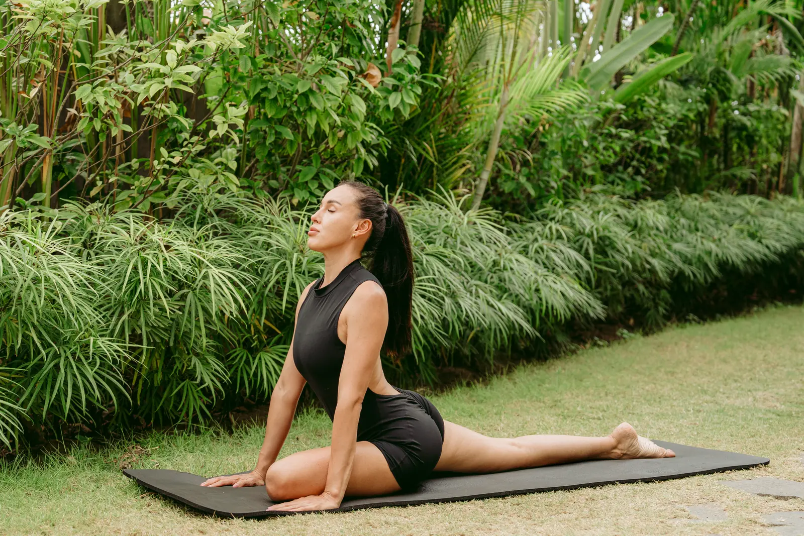 A guest holding a stretch on a mat in the garden
