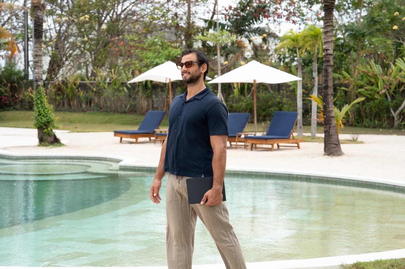 A guest carrying a tablet past the pool