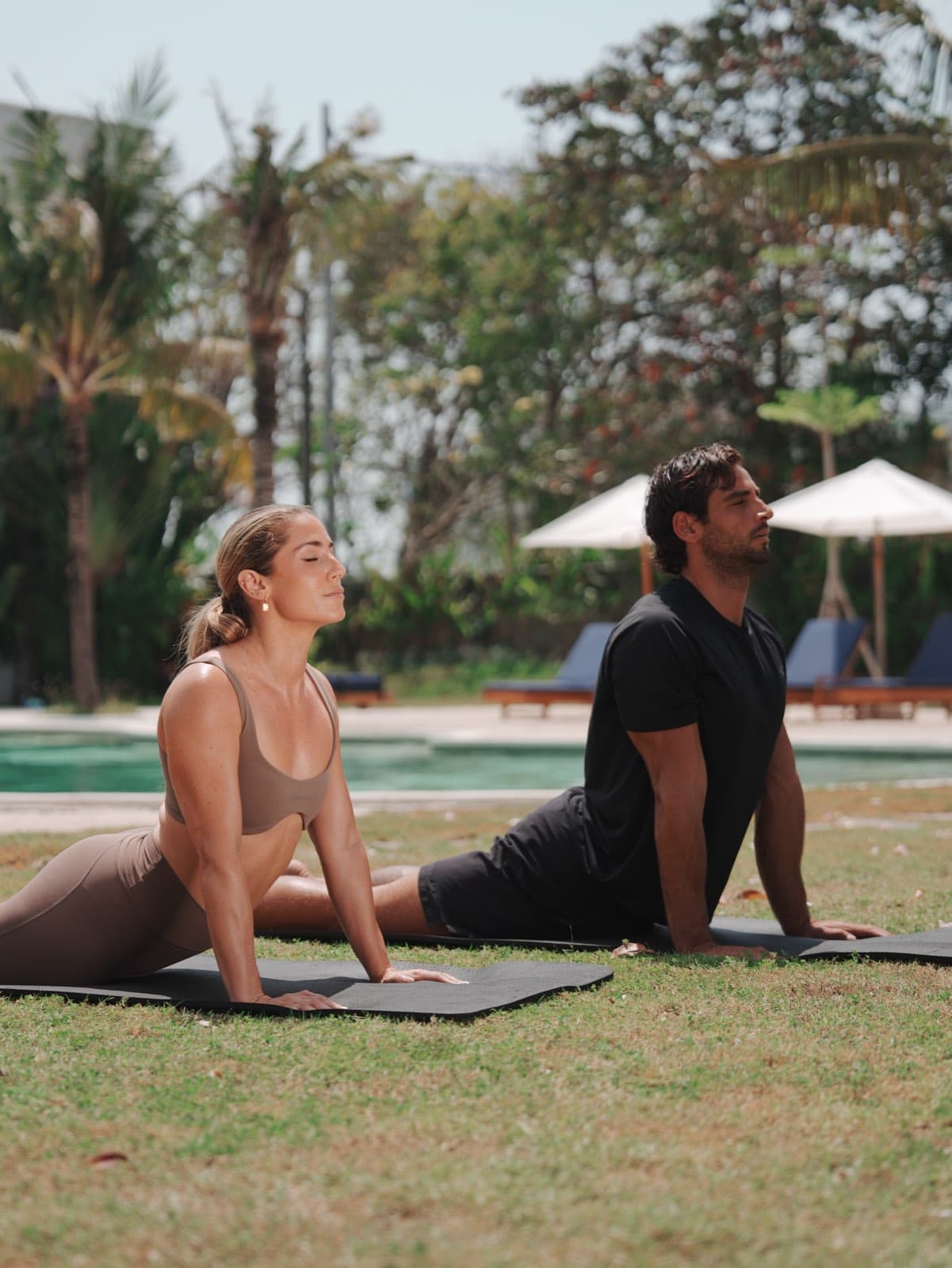 Two guests stretching on mats on the lawn