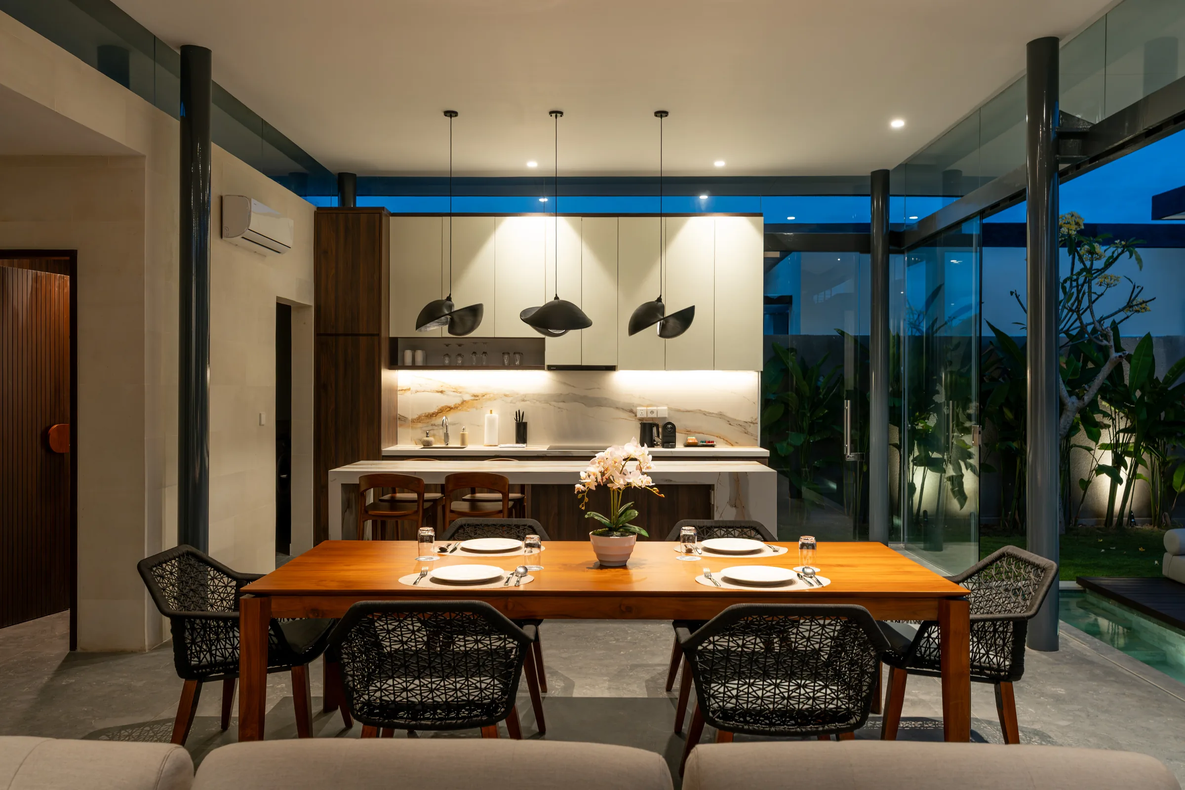 Kitchen, dining and living spaces connected to the pool at night