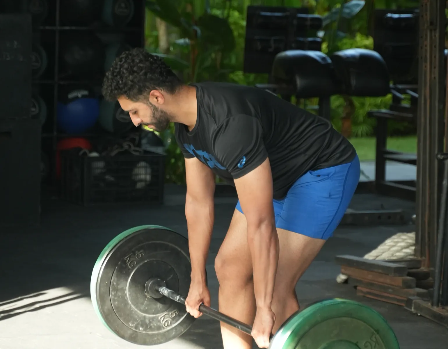 A guest lifting a barbell in the open-air gym at Pronoia Bali