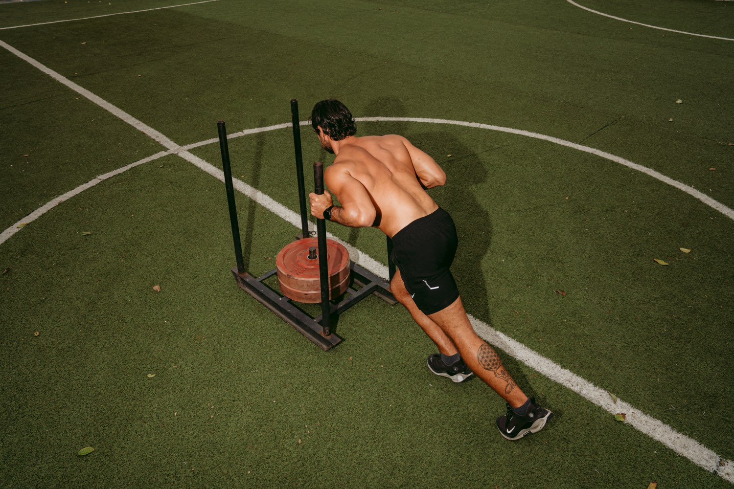 A guest pushing a weighted sled on the training turf at Pronoia Bali